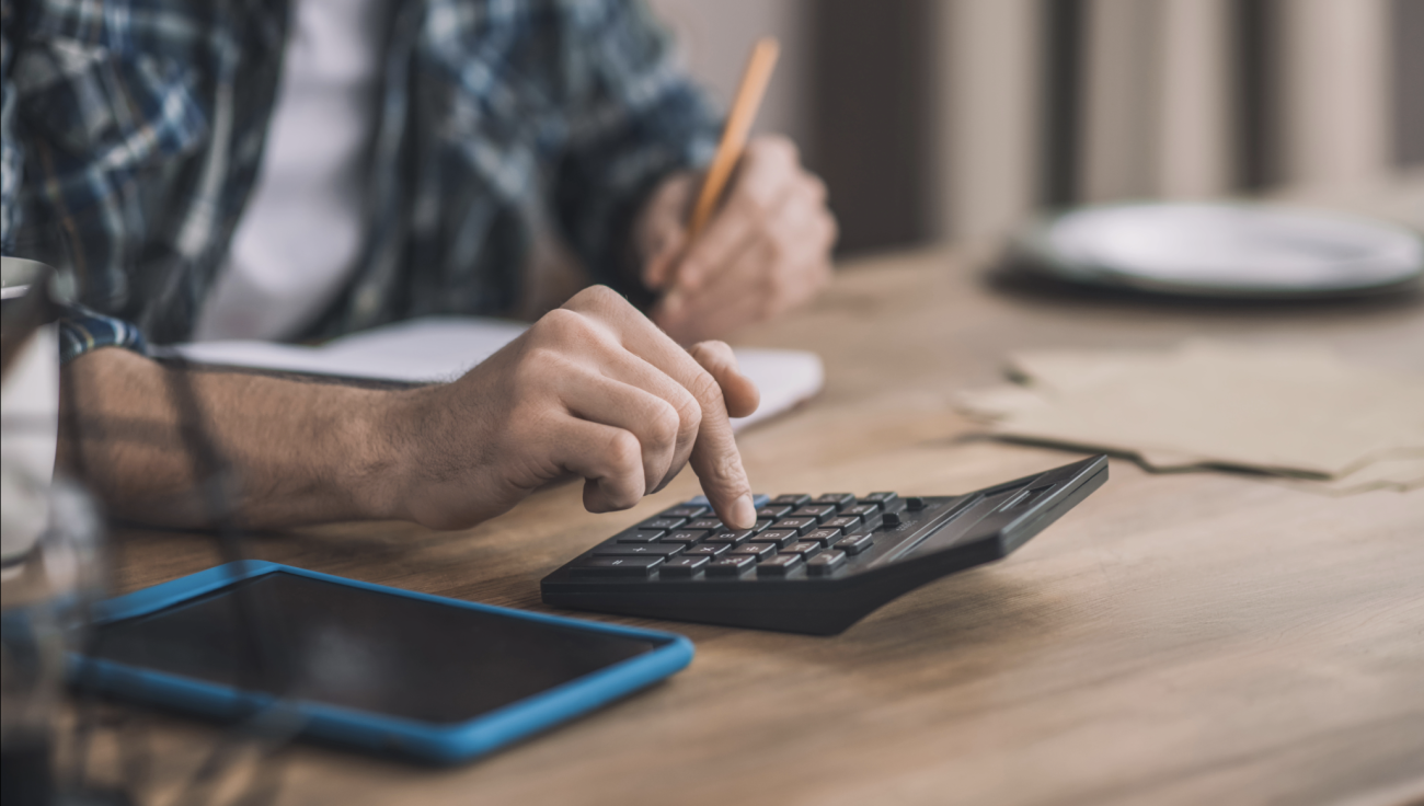 Autónomo haciendo cuentas con una calculadora y revisando facturas e impuestos