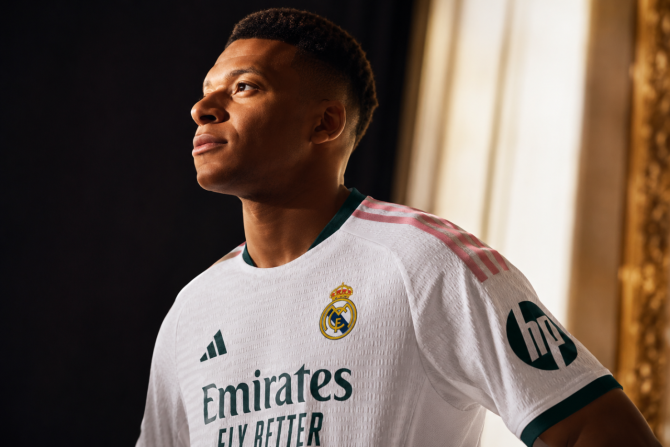 Kylian Mbappé posa con la nueva camiseta del Real Madrid 2026/27, con detalles en verde y rosa sobre la equipación blanca diseñada por Adidas. Kylian Mbappé posa con la nueva camiseta del Real Madrid 2026/27, con detalles en verde y rosa sobre la equipación blanca diseñada por Adidas.