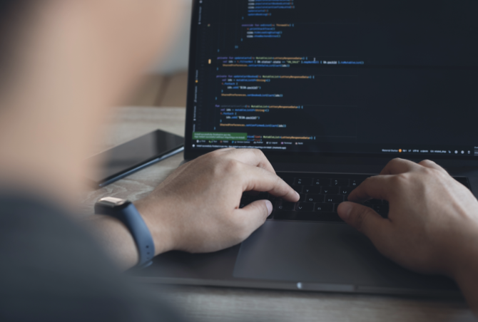 Programador escribiendo código en ordenador mientras la inteligencia artificial transforma el mercado laboral