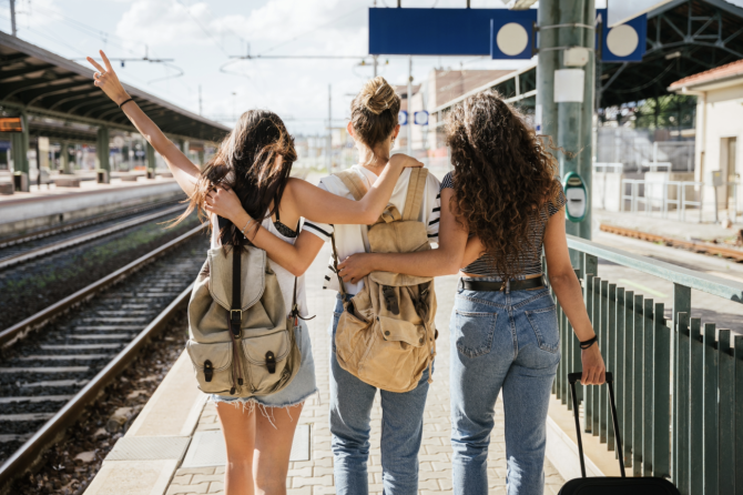 Grupo de jóvenes viajeros esperando un tren en una estación durante el verano, imagen representativa del programa Verano Joven 2026 y los descuentos en transporte.