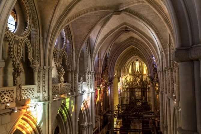 Interior de la Catedral de Cuenca iluminado por los colores de sus vidrieras contemporáneas, creando un singular juego de luces sobre la arquitectura gótica del templo.