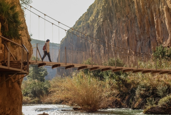 Senderista cruzando uno de los puentes colgantes de Chulilla sobre el cañón del río Turia en Valencia.