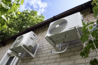 Unidades exteriores de aire acondicionado instaladas en la fachada de una vivienda durante un día de calor.