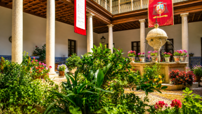 Patio histórico del Palacio Arzobispal de Toledo con columnas, fuente central y abundante vegetación.