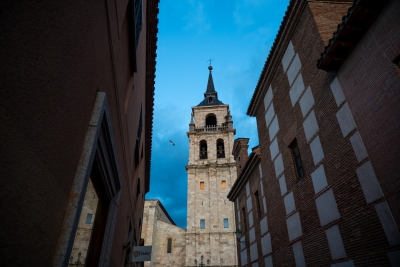 Torre histórica de Alcalá de Henares entre edificios de ladrillo al anochecer.